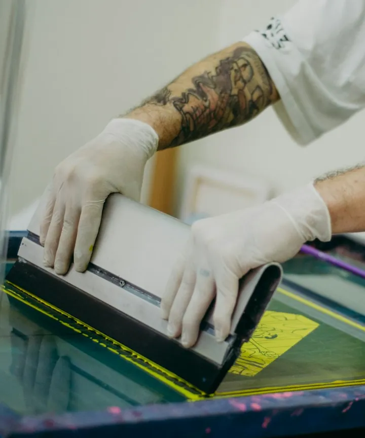 Operario con guantes pasando la rasqueta sobre una pantalla de serigrafía